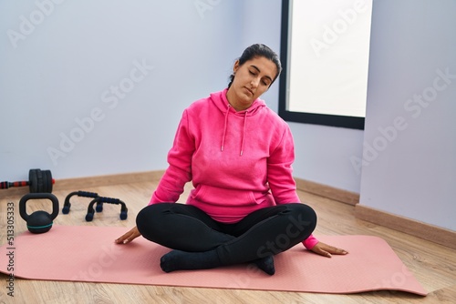 Young hispanic woman stretching at sport center