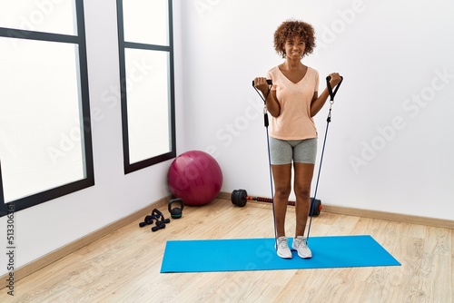 Young african american woman smiling confident training using elastic band at sport center