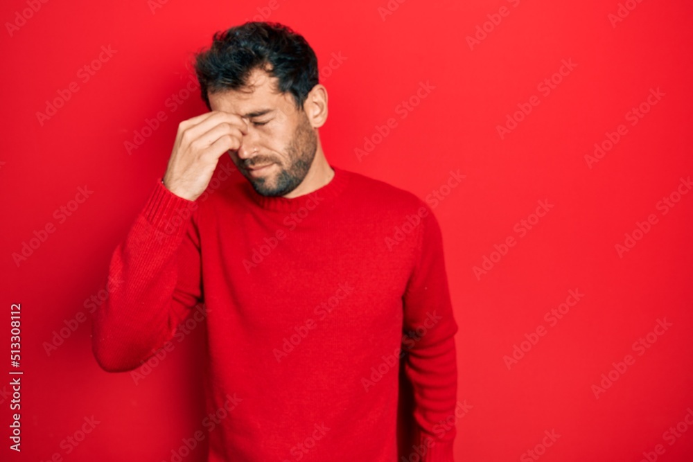 Handsome man with beard wearing casual red sweater tired rubbing nose and eyes feeling fatigue and headache. stress and frustration concept. Handsome man with beard wearing casual red sweater tired rubbing nose and eyes feeling fatigue and headache. stress and frustration concept.