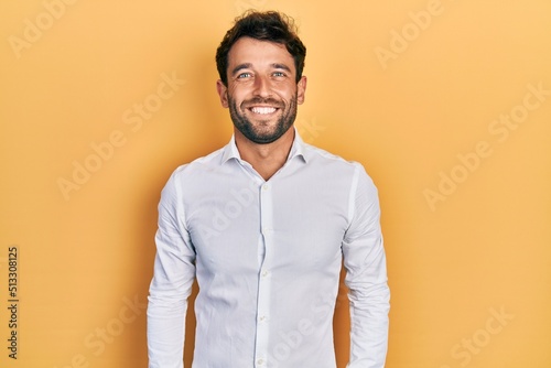 Handsome man with beard wearing casual white t shirt with a happy and cool smile on face. lucky person.