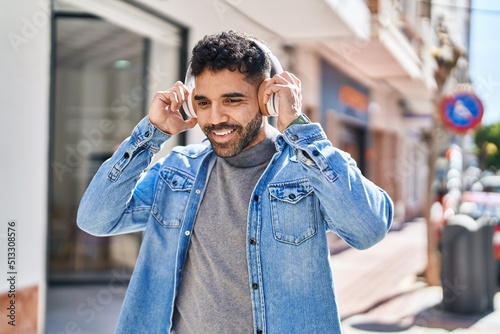 Young hispanic man smiling confident listening to music at street