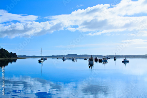 Small sailing boats reflected in calm water of the bay. Beautiful morning at a harbour, Far North, New Zealand