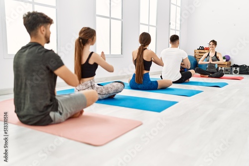 Group of young people having yoga class with personal trainer at sport center.