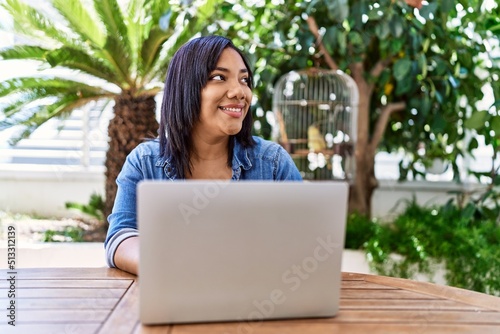 Hispanic brunette woman using laptop at the terrace