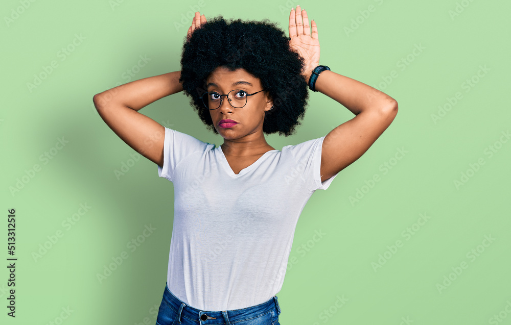 Young african american woman wearing casual white t shirt doing bunny ears gesture with hands palms looking cynical and skeptical. easter rabbit concept. Young african american woman wearing casual white t shirt doing bunny ears gesture with hands palms looking cynical and skeptical. easter rabbit concept.