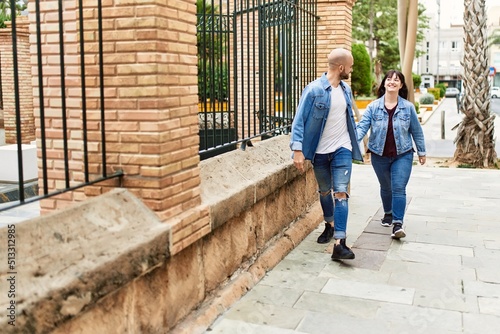 Young hispanic couple smiling happy walking with hands together at the city.