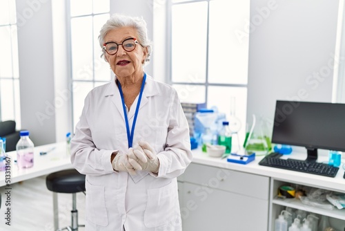 Senior grey-haired woman wearing scientist uniform standing at laboratory
