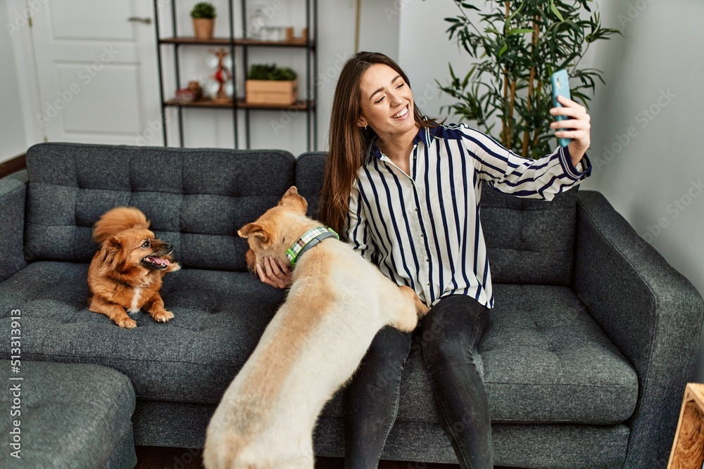 Young hispanic woman make selfie by the smartphone sitting on sofa with ...