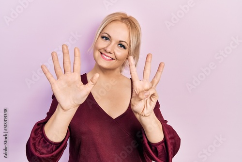 Young blonde woman wearing casual winter sweater showing and pointing up with fingers number eight while smiling confident and happy.