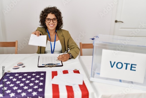 Young hispanic woman smiling confident holding vote working at electoral college