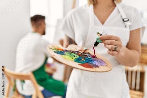Young caucasian couple drawing at art studio. Girl mixing colors on palette. © Krakenimages.com