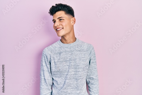 Young hispanic man wearing casual clothes looking away to side with smile on face, natural expression. laughing confident.