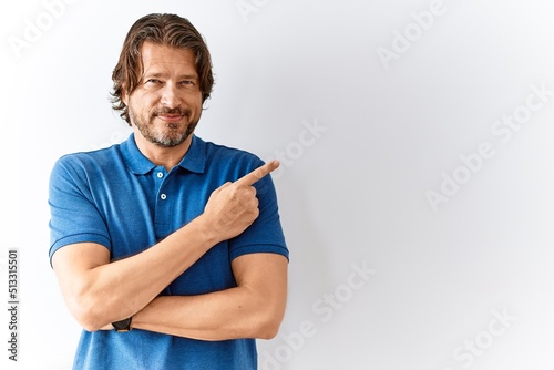 Handsome middle age man standing together over isolated background pointing with hand finger to the side showing advertisement, serious and calm face