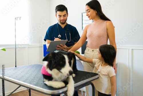 Hispanic vet giving a medical diagnosis to the dog owners at the hospital