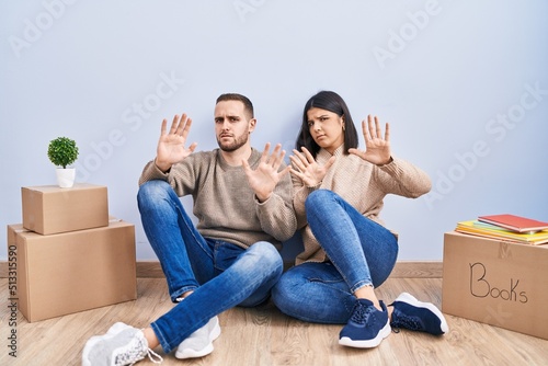 Young couple moving to a new home moving away hands palms showing refusal and denial with afraid and disgusting expression. stop and forbidden. © Krakenimages.com