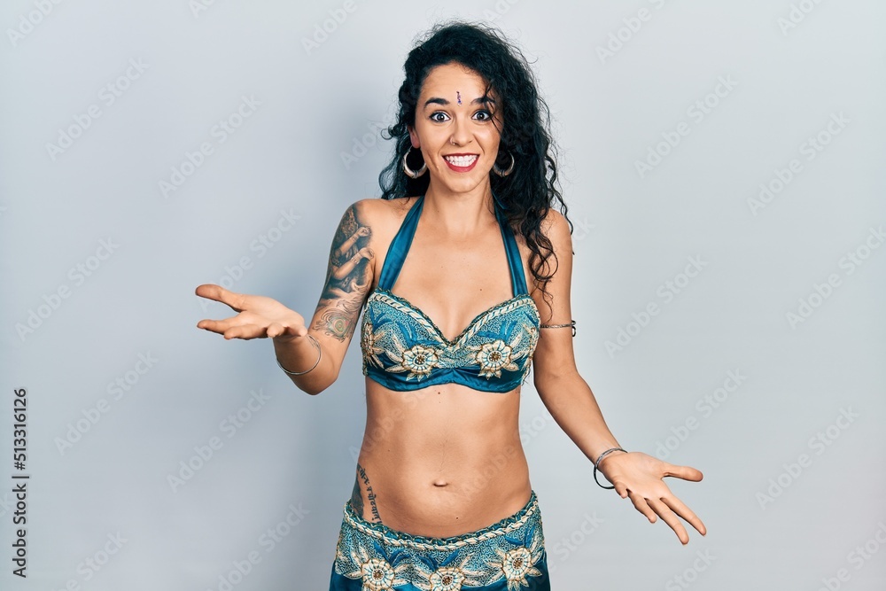 Fototapeta premium Young woman wearing bindi and traditional belly dance clothes smiling cheerful with open arms as friendly welcome, positive and confident greetings
