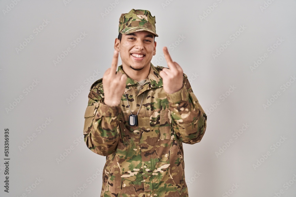 Young arab man wearing camouflage army uniform showing middle finger doing fuck you bad expression, provocation and rude attitude. screaming excited Young arab man wearing camouflage army uniform showing middle finger doing fuck you bad expression, provocation and rude attitude. screaming excited