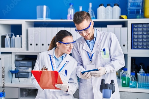 Man and woman scientists using smartphone write on document at laboratory