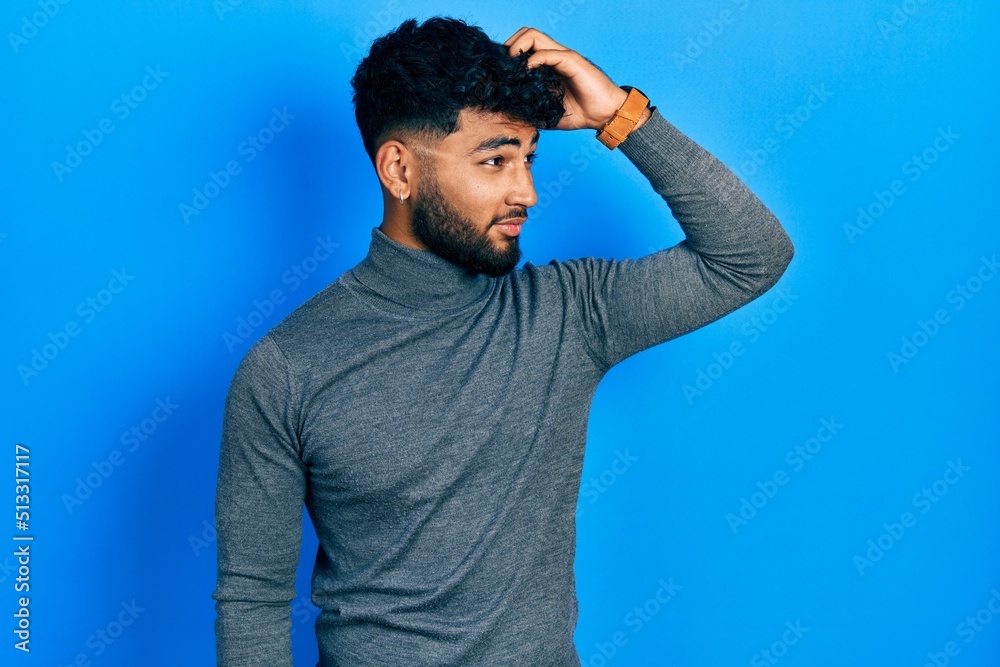 Arab man with beard wearing turtleneck sweater smiling confident touching hair with hand up gesture, posing attractive and fashionable Arab man with beard wearing turtleneck sweater smiling confident touching hair with hand up gesture, posing attractive and fashionable