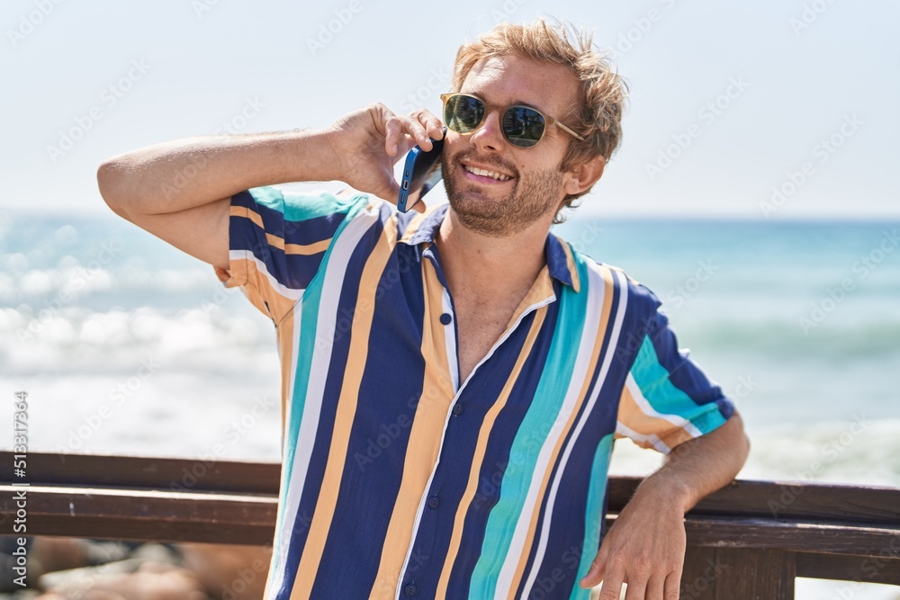 Young man tourist smiling confident talking on the smartphone at seaside