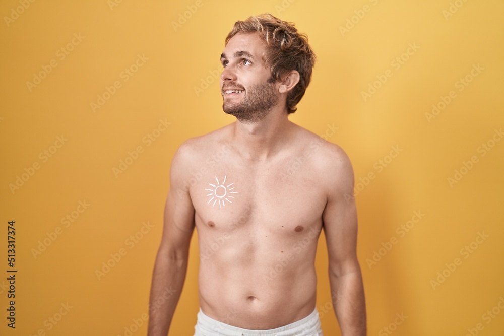 Fototapeta premium Caucasian man standing shirtless wearing sun screen looking away to side with smile on face, natural expression. laughing confident.