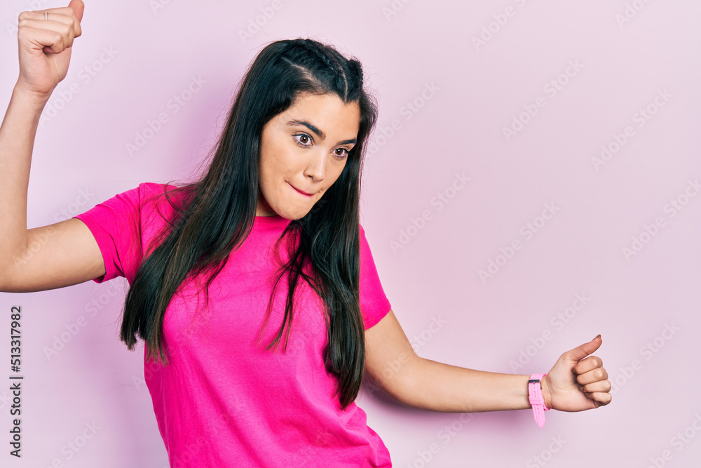 Young hispanic girl wearing casual pink t shirt dancing happy and cheerful, smiling moving casual and confident listening to music Young hispanic girl wearing casual pink t shirt dancing happy and cheerful, smiling moving casual and confident listening to music