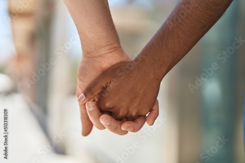 Man and woman interracial couple with hands together at street