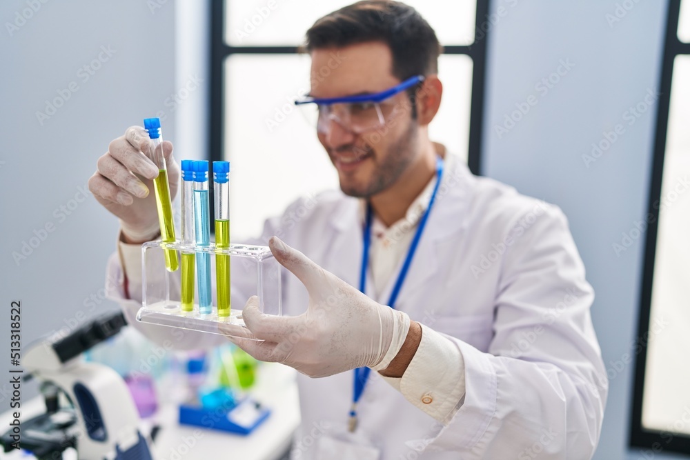 Young hispanic man scientist holding test tubes at laboratory