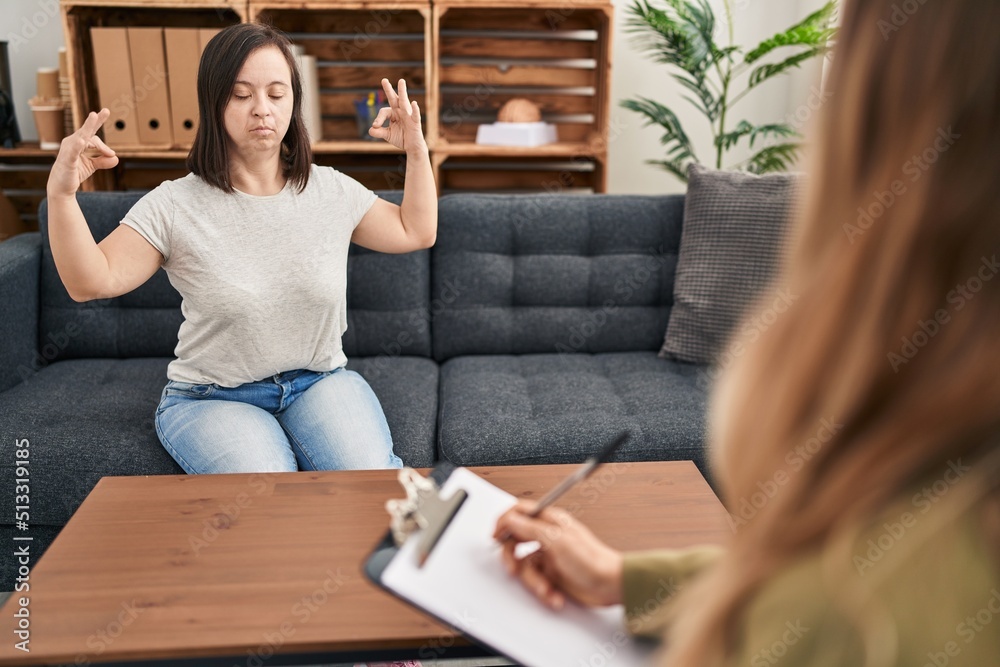 Hispanic girl with down syndrome doing therapy relax and smiling with eyes closed doing meditation gesture with fingers. yoga concept. Hispanic girl with down syndrome doing therapy relax and smiling with eyes closed doing meditation gesture with fingers. yoga concept.
