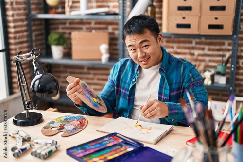 Young chinese man artist drawing on notebook at art studio