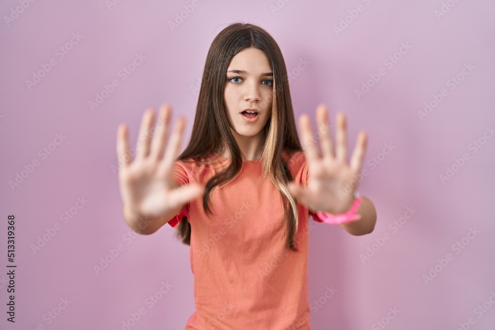 Teenager girl standing over pink background doing stop gesture with hands palms, angry and frustration expression Teenager girl standing over pink background doing stop gesture with hands palms, angry and frustration expression