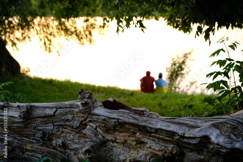 Happy senior couple sitting in summer near lake during sunset