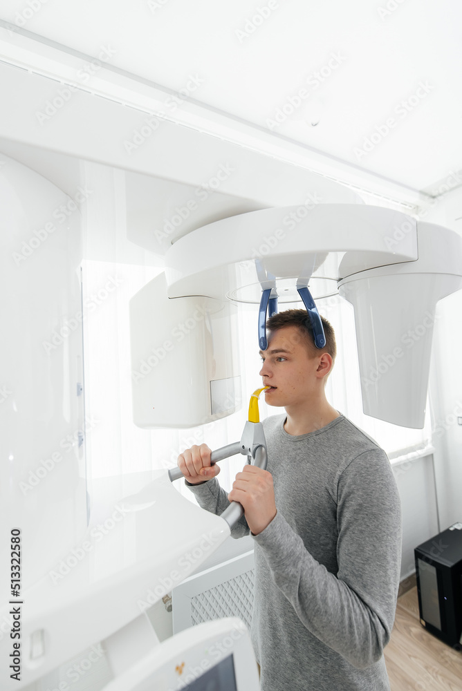 A young man has a computed tomography of the jaw, a circular snapshot of the jaw in modern dentistry. Prevention of caries, prosthetics and dental treatment. Radiology, panoramic scanner. A young man has a computed tomography of the jaw, a circular snapshot of the jaw in modern dentistry. Prevention of caries, prosthetics and dental treatment. Radiology, panoramic scanner.