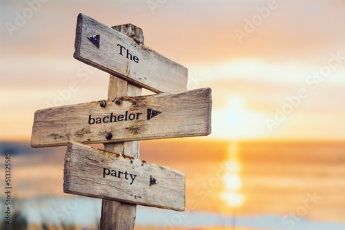 the bachelor party text quote on wooden crossroad signpost outdoors on beach with pink pastel sunset colors. Romantic theme. photo