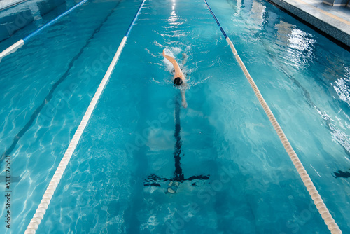 A young man trains and swims in a modern swimming pool. Sports development. Preparation for competitions, and a healthy lifestyle. Water treatments and a healthy lifestyle.