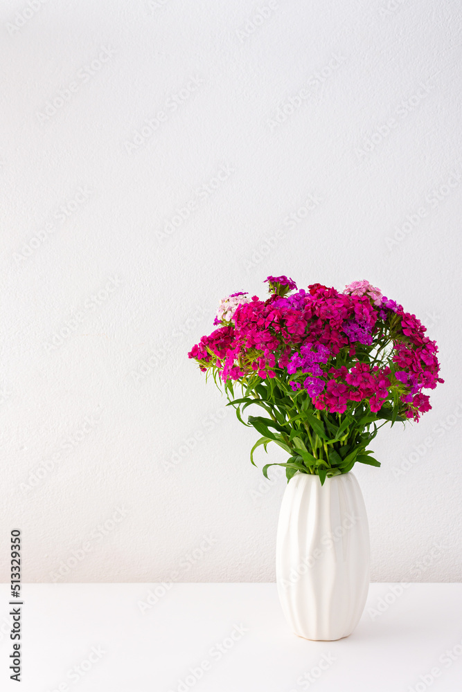 Beautiful summer carnation flowers in a white vase, part of home interior Beautiful summer carnation flowers in a white vase, part of home interior