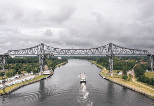 Obraz na płótnie Cargo ship (freighter) passing Rendsburg High Bridge (Rendsburger Hochbrücke) over Kiel Canal (Schleswig-holstein) w salonie