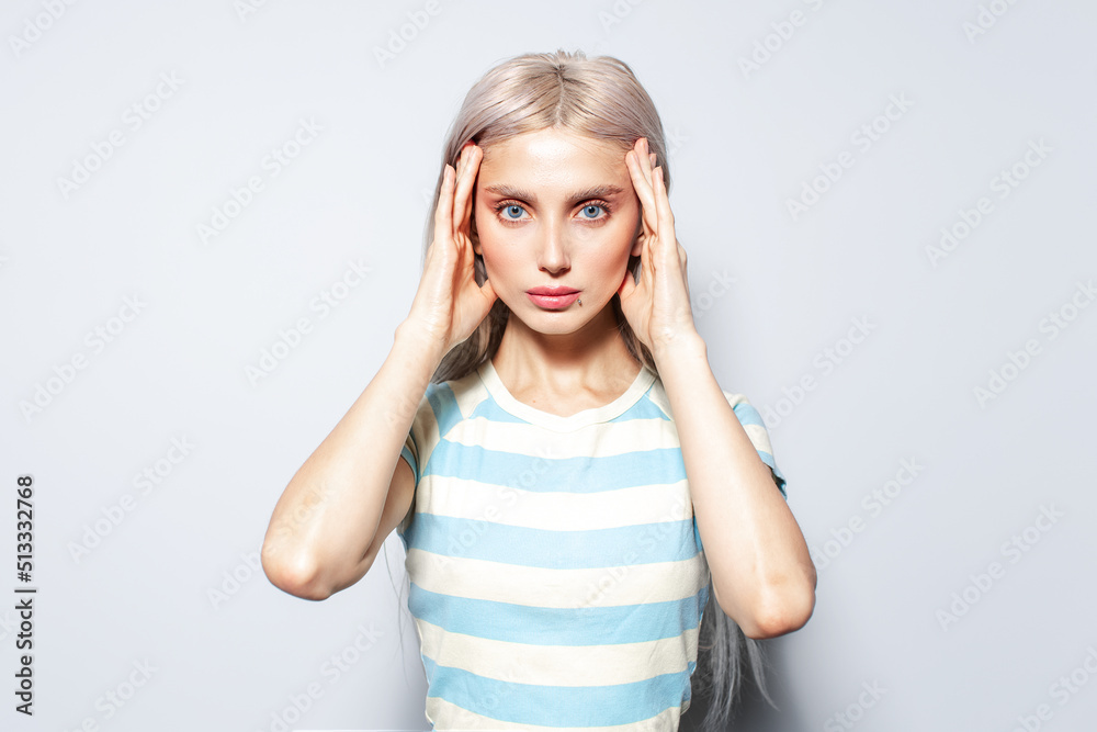 Portrait of beautiful blonde girl holding hands on temples, on white background. Portrait of beautiful blonde girl holding hands on temples, on white background.