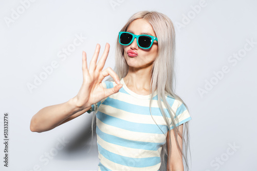 Portrait of beautiful girl showing ok gesture, on white background.