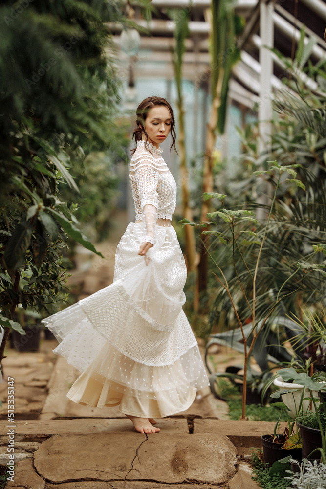 A young girl in a vintage dress in a tropical greenhouse.
