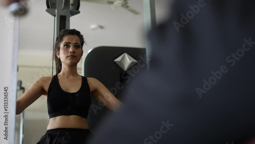 A young Indian girl doing musculer execrise front on glass.female fitness concept.Indian girl execrise with machines in the gym.close up shot. photo