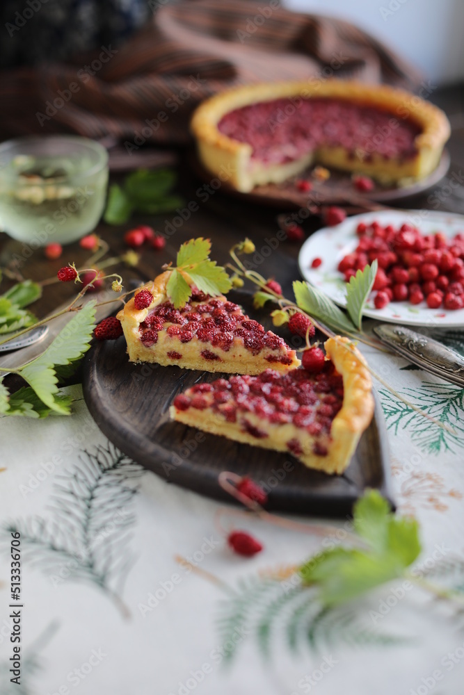 Two pieces of pie. Open almond tart with wild strawberries on a table with a tablecloth. Homemade cakes with hand-picked seasonal berries. Two pieces of pie. Open almond tart with wild strawberries on a table with a tablecloth. Homemade cakes with hand-picked seasonal berries.