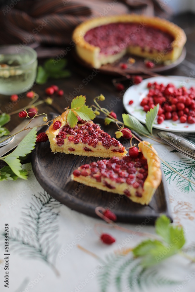 Two pieces of pie. Open almond tart with wild strawberries on a table with a tablecloth. Homemade cakes with hand-picked seasonal berries. Two pieces of pie. Open almond tart with wild strawberries on a table with a tablecloth. Homemade cakes with hand-picked seasonal berries.