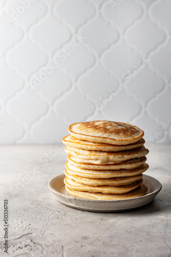 Stack of pancakes on textured background with tile in back and copy space