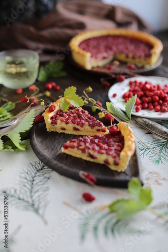 Two pieces of pie. Open almond tart with wild strawberries on a table with a tablecloth. Homemade cakes with hand-picked seasonal berries.