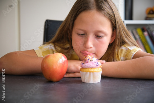 the girl chooses between a cupcake and an apple