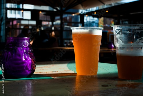 Photography Closeup shot of beer in plastic cups with the sunlight hitting it on a table in