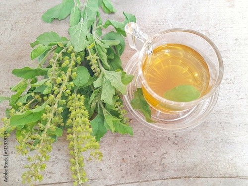 Tulsi tea is served in a cup with fresh leaves on the side of the selected focus.