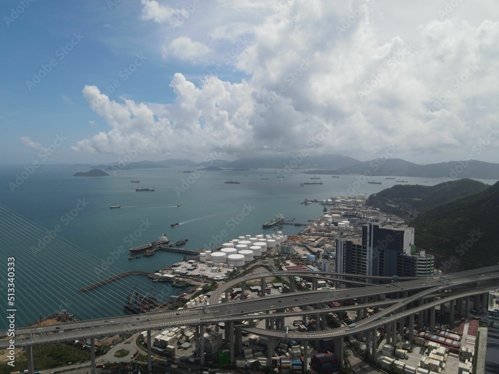 Aerial view of a bridge and dense coastline buildings under the cloudy sky in Hong Kong