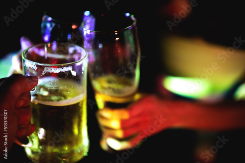 Close Up on hands Celebration toast with Beer in a Nightlife Atmospheric Mood Lights